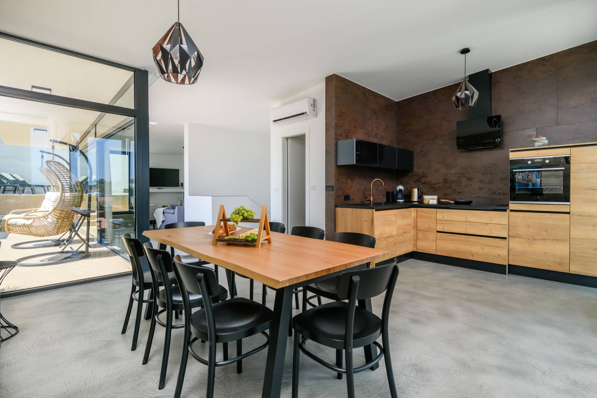 A modern kitchen with wooden cabinets, a built-in oven, and a TV mounted above the counter.