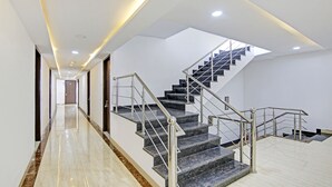 A modern hotel interior with a long hallway, a staircase with metal railings, and a skylight above. - Treebo Royal Empire Adarsh Nagar, Chandigarh (Kharar)