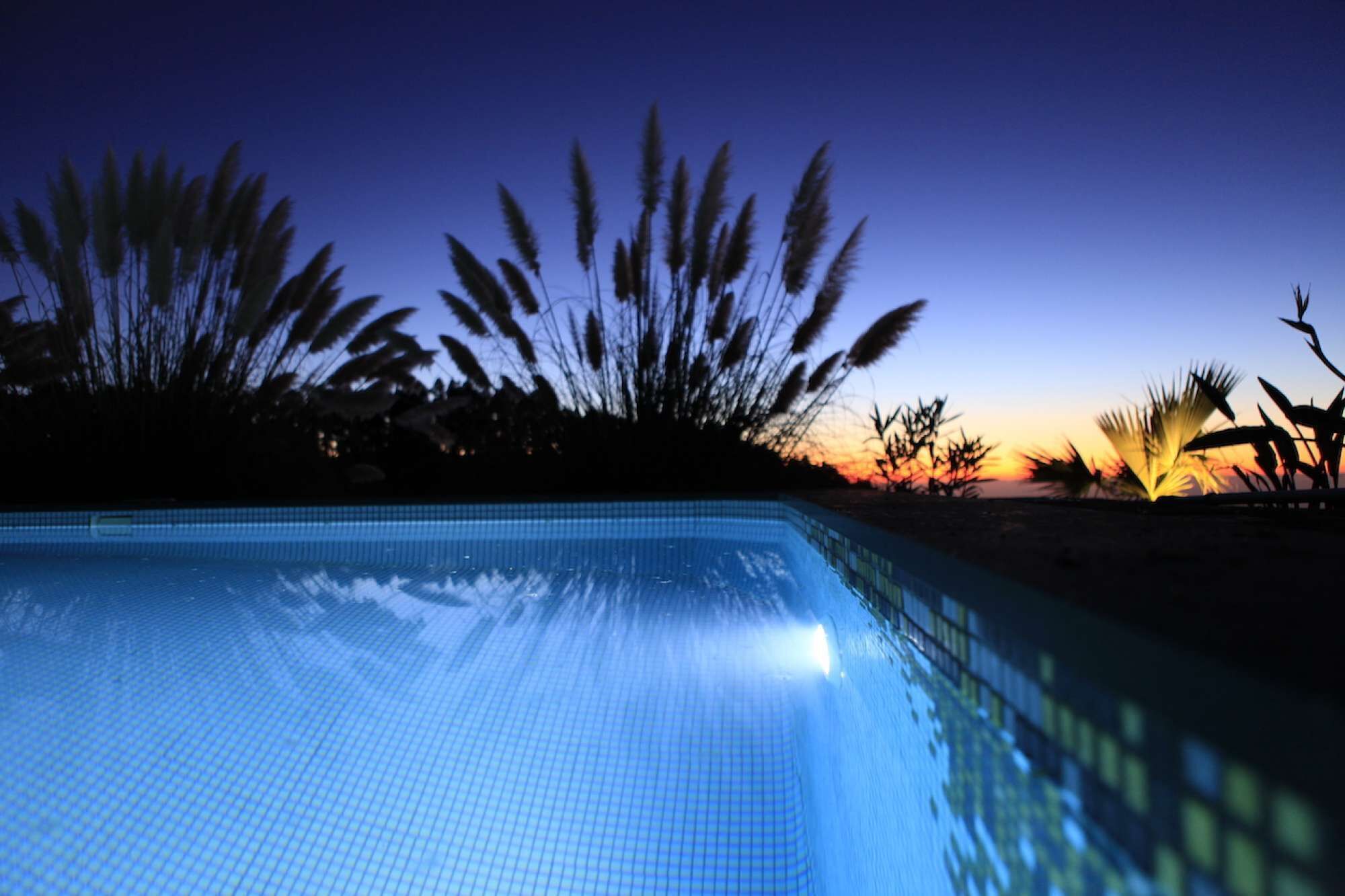 Una piscina al atardecer con un ocaso en el fondo.