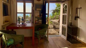 A cozy room with a wooden table, wicker chairs, a view of the outdoors, and a rustic stove.