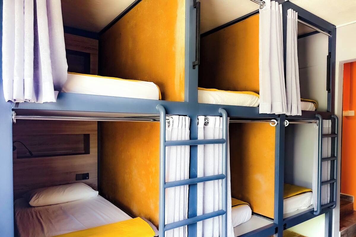 A bunk bed room with a wooden headboard, white bedding, and curtains.