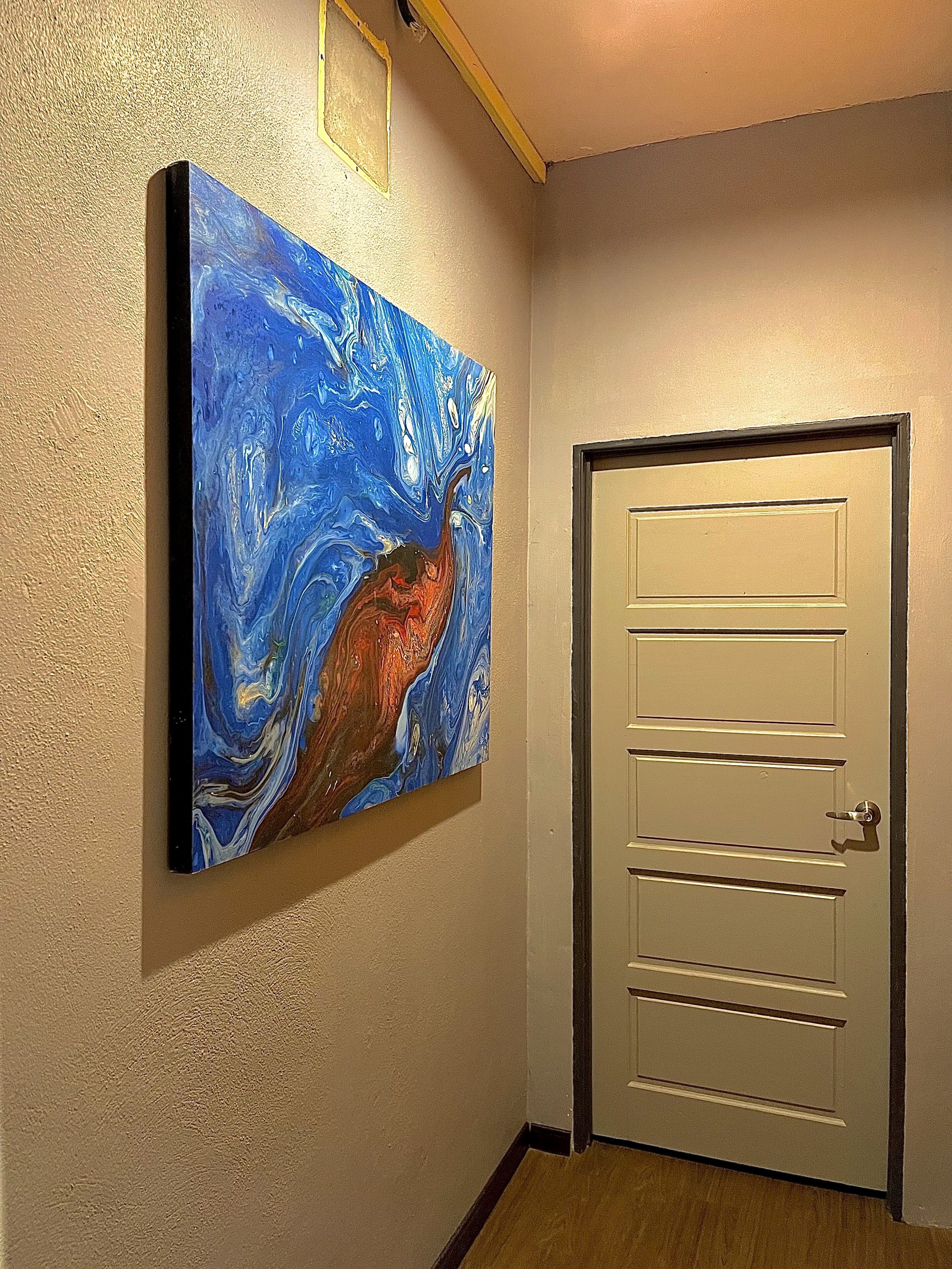 A hallway with a door and a painting on the wall.