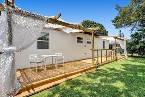 Une maison dotée d’un patio couvert, de murs blancs et d’une terrasse en bois.