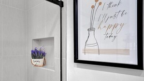 Una cita enmarcada en una pared, una planta de lavanda en maceta y una puerta con picaporte negro.