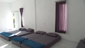 Two single beds with matching headboards and footboards, a large window with a curtain, and a tiled floor.