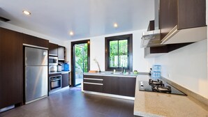 Cocina moderna con armarios oscuros, electrodomésticos de acero inoxidable y un amplio ventanal con vistas a zonas verdes.