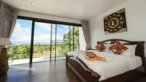 Un dormitorio con un ventanal grande, una cama con ropa de cama blanca y un adorno en la pared.