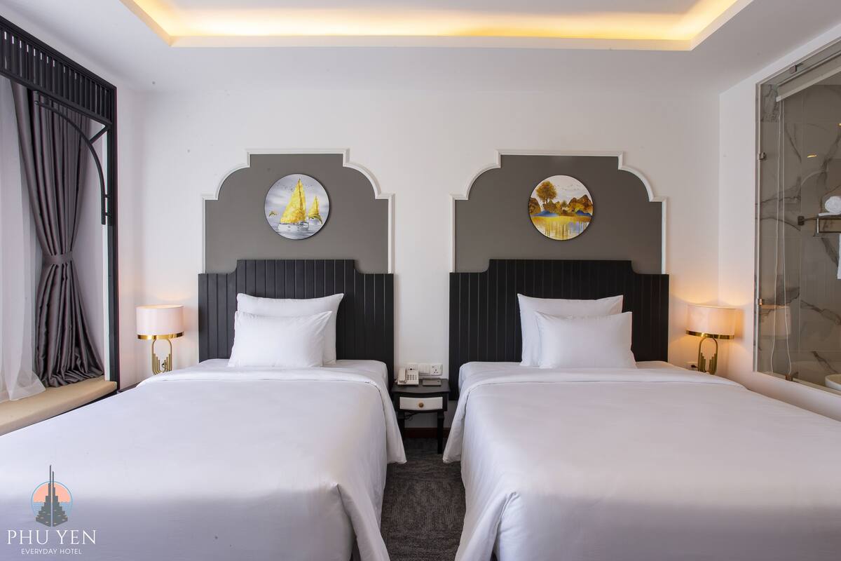 Een hotelkamer met twee bedden, een douche en uitzicht op de stad.