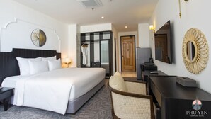 A hotel room with a large bed, a desk, a chair, a mirror, and a wall clock. - Phú Yên Everyday Hotel (Tuy Hoa)