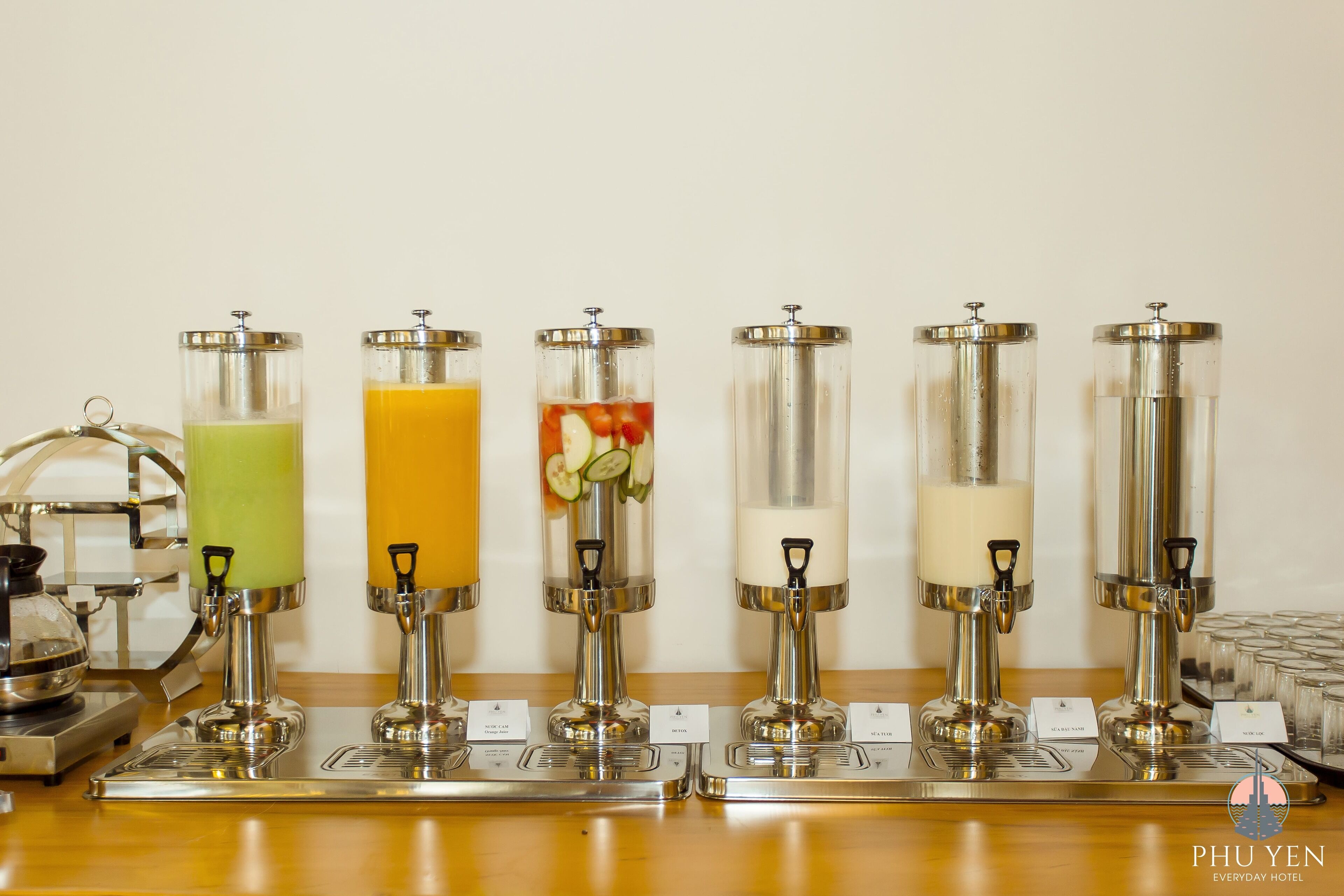 A beverage dispenser station with multiple options including green, orange, and white drinks, and a coffee machine on the left.