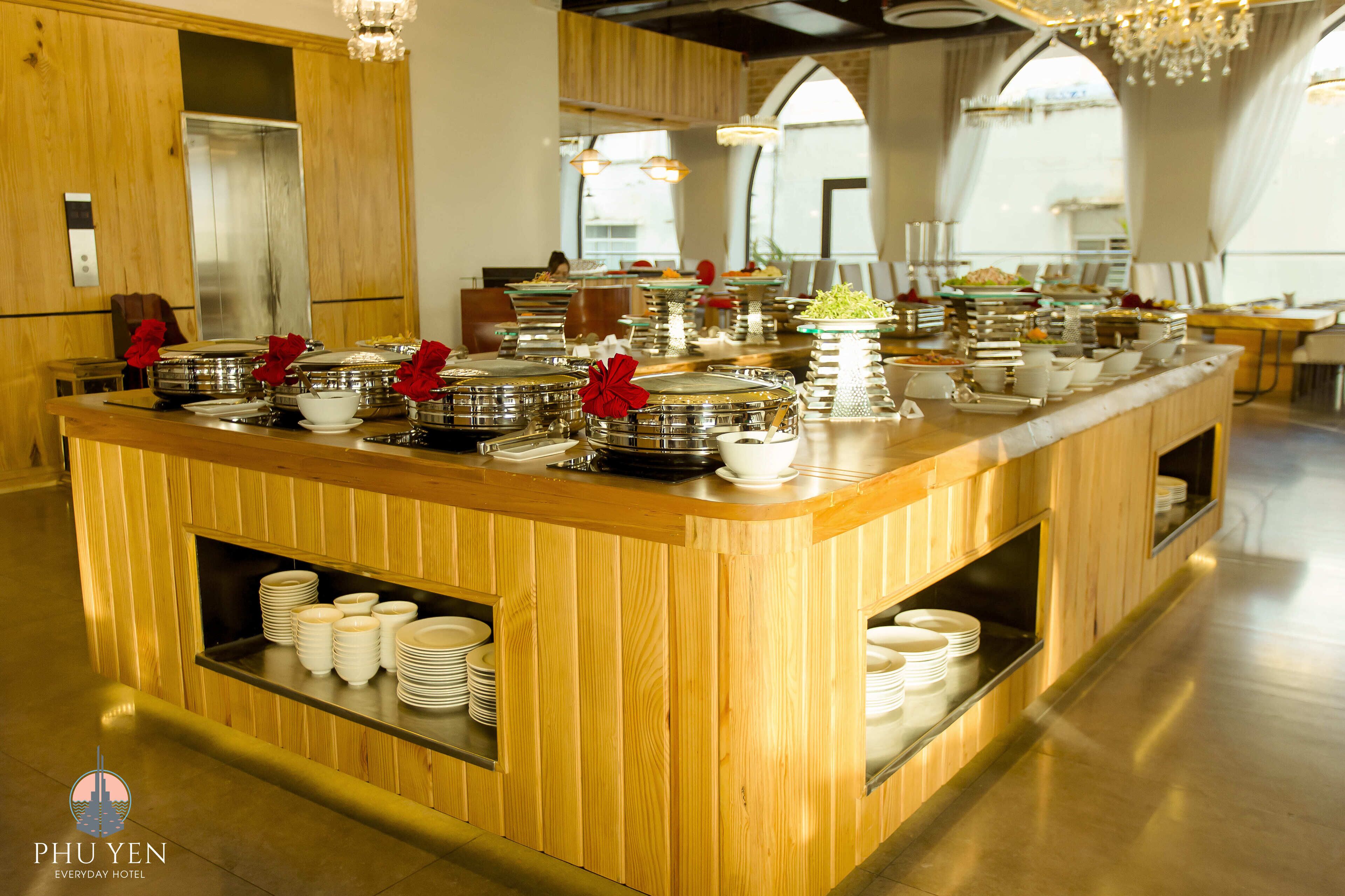 A buffet setup with multiple serving stations, wooden paneling, and a chandelier.