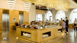 A modern hotel lobby with a central buffet area, wooden paneling, and chandeliers. - Phú Yên Everyday Hotel (Tuy Hoa)