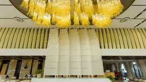 A modern lobby with a central seating area, a decorative yellow chandelier, and a marble wall with the name "PHU YEN". - Phú Yên Everyday Hotel (Tuy Hoa)