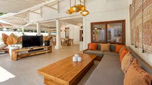 A spacious living area with a wooden coffee table, a sofa, and a television.