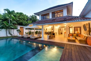 Une maison moderne dotée d’une piscine, d’un espace salon extérieur et d’une terrasse bien éclairée.