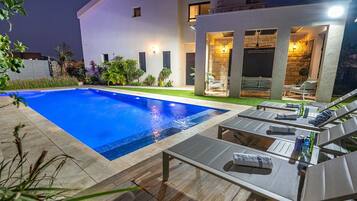 Relax by the pool surrounded by lush greenery and comfortable lounge chairs.