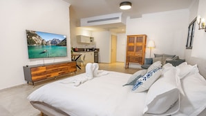 A hotel room with a large bed, a TV mounted on the wall, a wooden dresser, a desk with a chair, and a wardrobe. - Tavor View Suites (Galil Tachton)