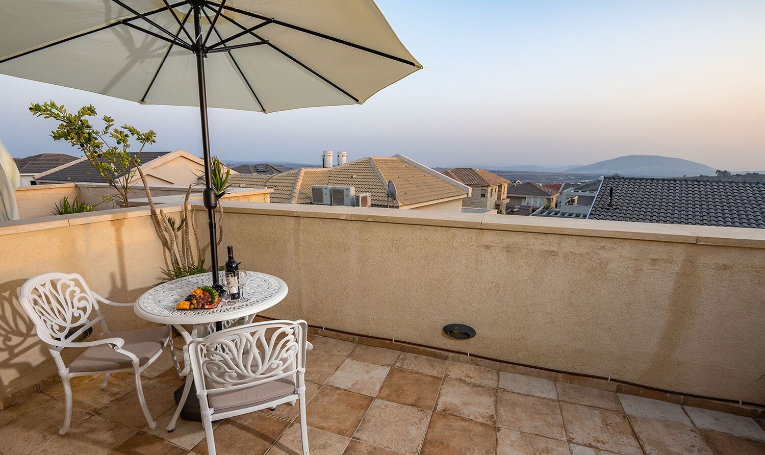 Una terrazza sul tetto con tavolo e sedie, un ombrellone grande e vista sulla città.