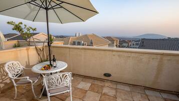 Una terrazza sul tetto con tavolo e sedie, un ombrellone grande e vista sulla città.