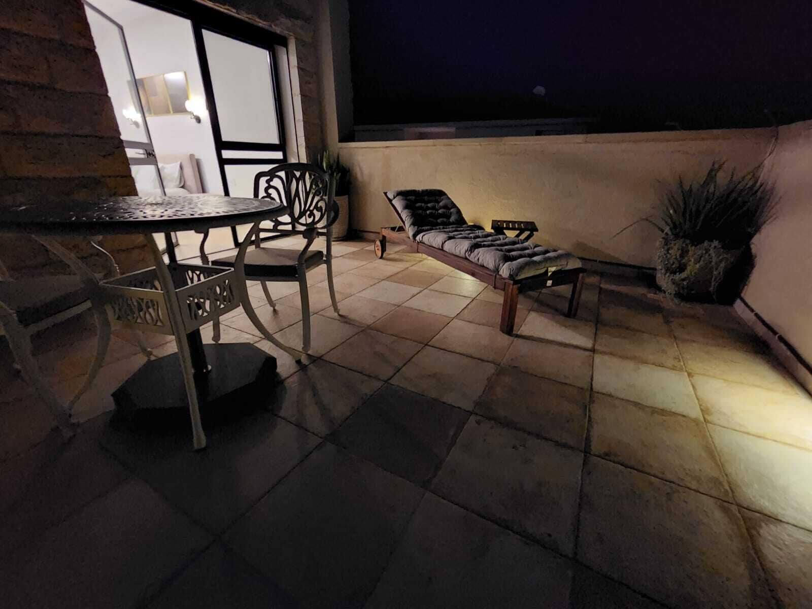 Een dakterras met een tafel en stoelen, een lounge stoel en een plant in een pot.