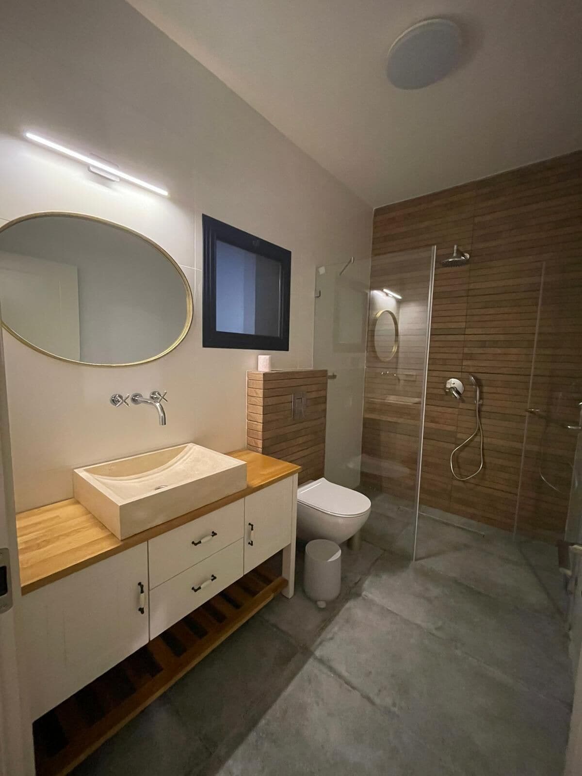 A modern bathroom with a vanity, sink, mirror, toilet, and shower.