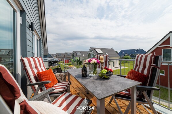 A terrace with outdoor seating, a table with drinks and fruit, and a view of neighboring houses.
