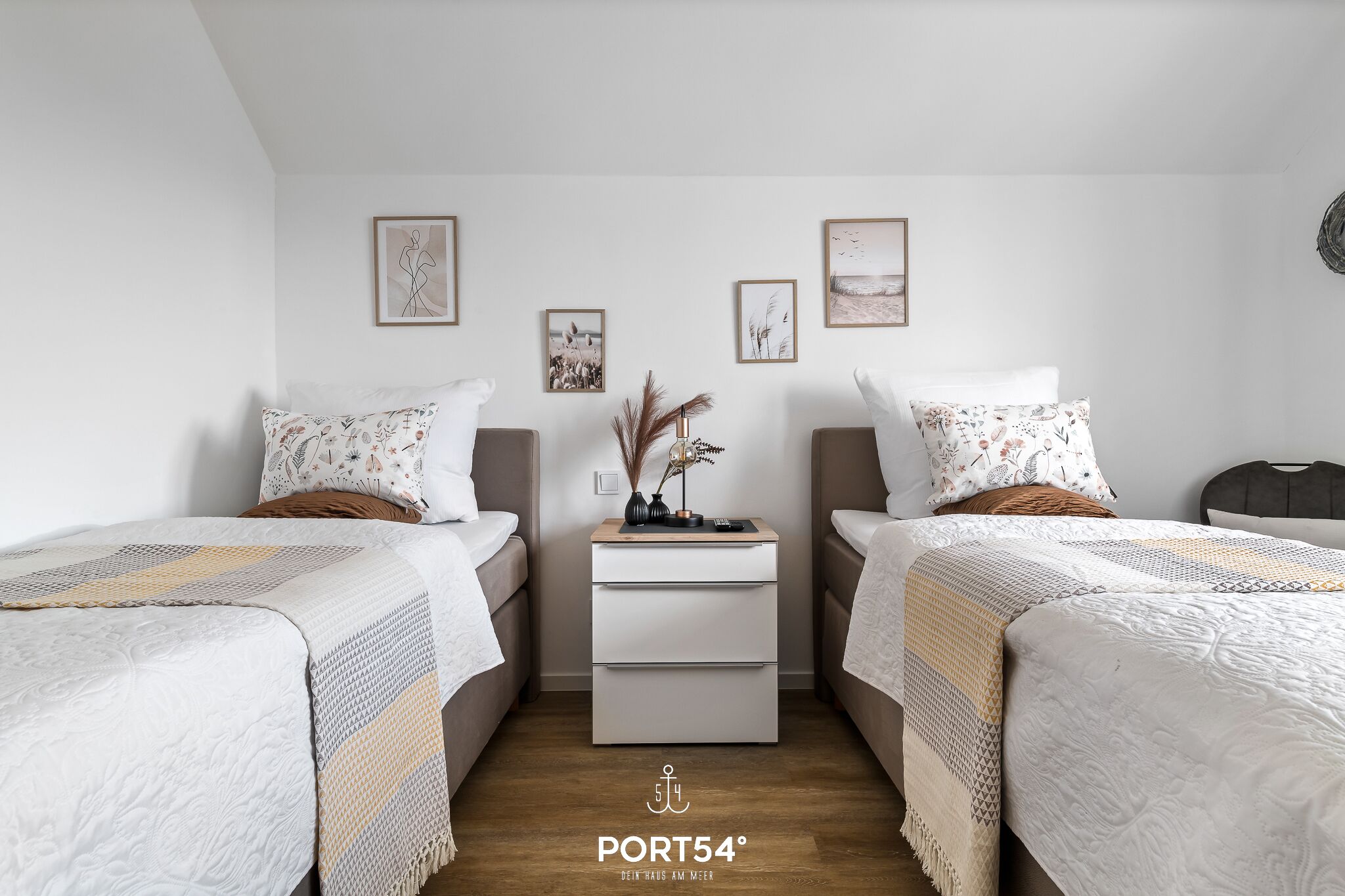 Une chambre moderne avec deux lits, une table de chevet et des œuvres d’art murales.