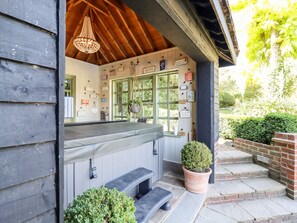A cozy outdoor seating area with a wooden ceiling, a hanging chandelier, and a variety of signs on the wall. - Willow Cottage (Dartford)