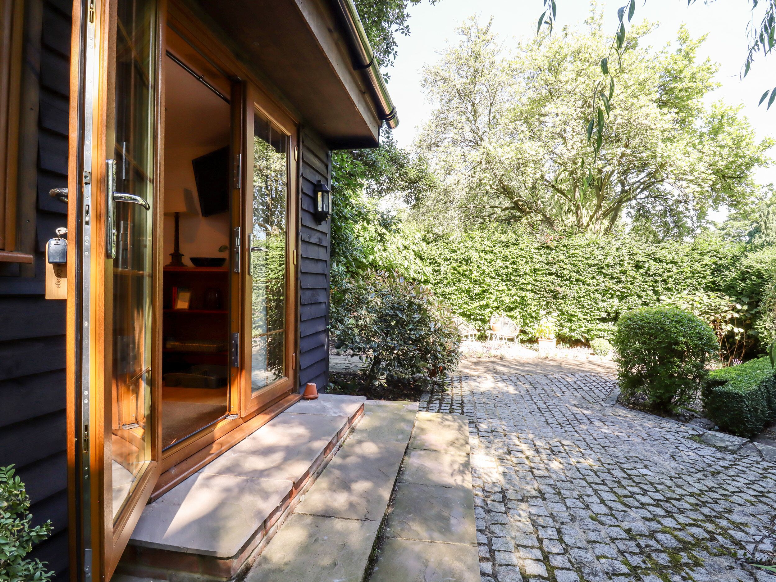 A wooden house with a glass door leading to a paved area.