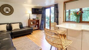 A living room with a sofa, a TV, a table, and chairs. - Willow Cottage (Dartford)