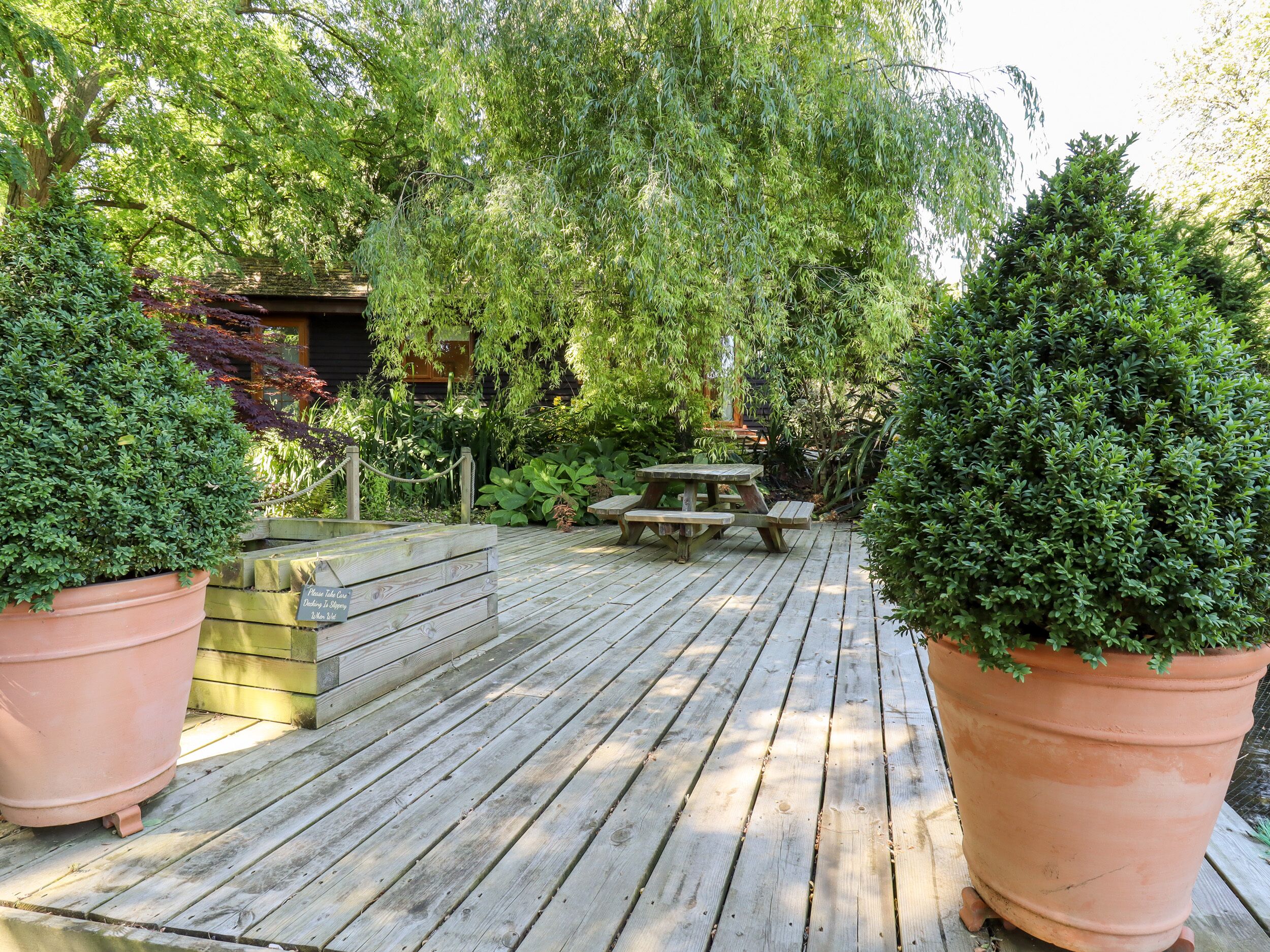 A wooden deck with a picnic table and potted plants.