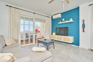 A living room with a sofa, a coffee table, a TV, and a blue accent wall.