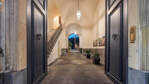 A hallway with a staircase leading to a balcony, potted plants, and artwork on the walls. - Luxury Historic Villa near Taormina/Catania/Mount Etna by SicilianRelaxingHomes (Giarre)