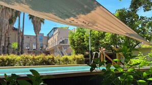 A pool area with a view of multi-story buildings, a covered seating area, and lush greenery. - Luxury Historic Villa near Taormina/Catania/Mount Etna by SicilianRelaxingHomes (Giarre)