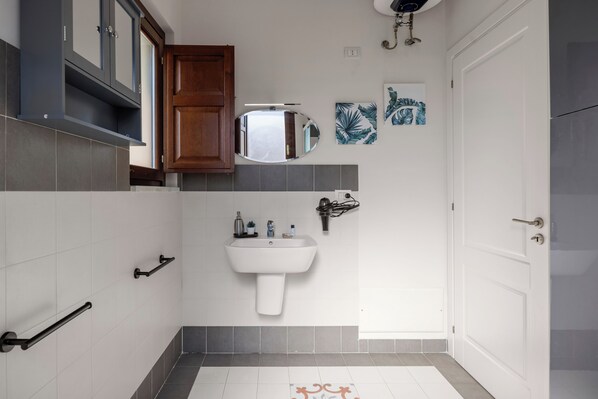 Un baño con lavamanos blanco, armarios de madera, un espejo y una puerta.