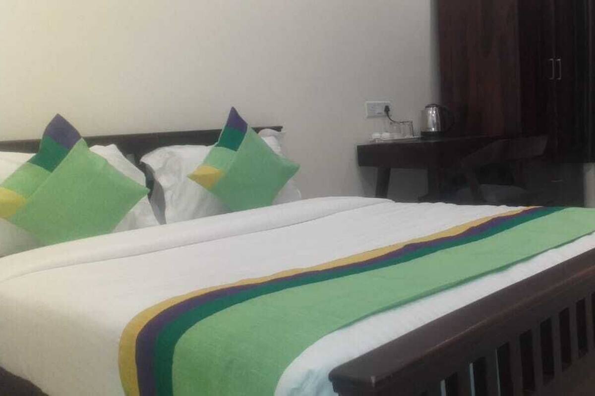 Un lit avec une couvre-lit à rayures blanches et vertes, une tête de lit en bois et deux coussins verts.