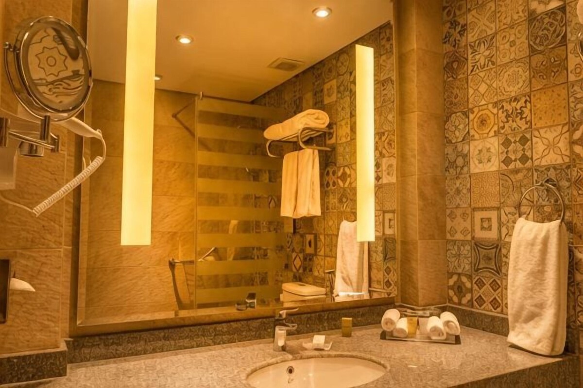 A bathroom with a large mirror, a sink, a towel rack, and a shower area.