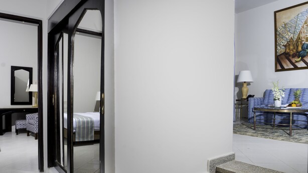 A hotel room with a bed, a desk with a lamp, a chair, and a window. - Safir Dahab Resort (Dahab)