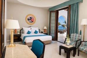 A hotel room with a bed, two bedside tables, a desk, a chair, and a view of the sea. - Safir Dahab Resort (Dahab)