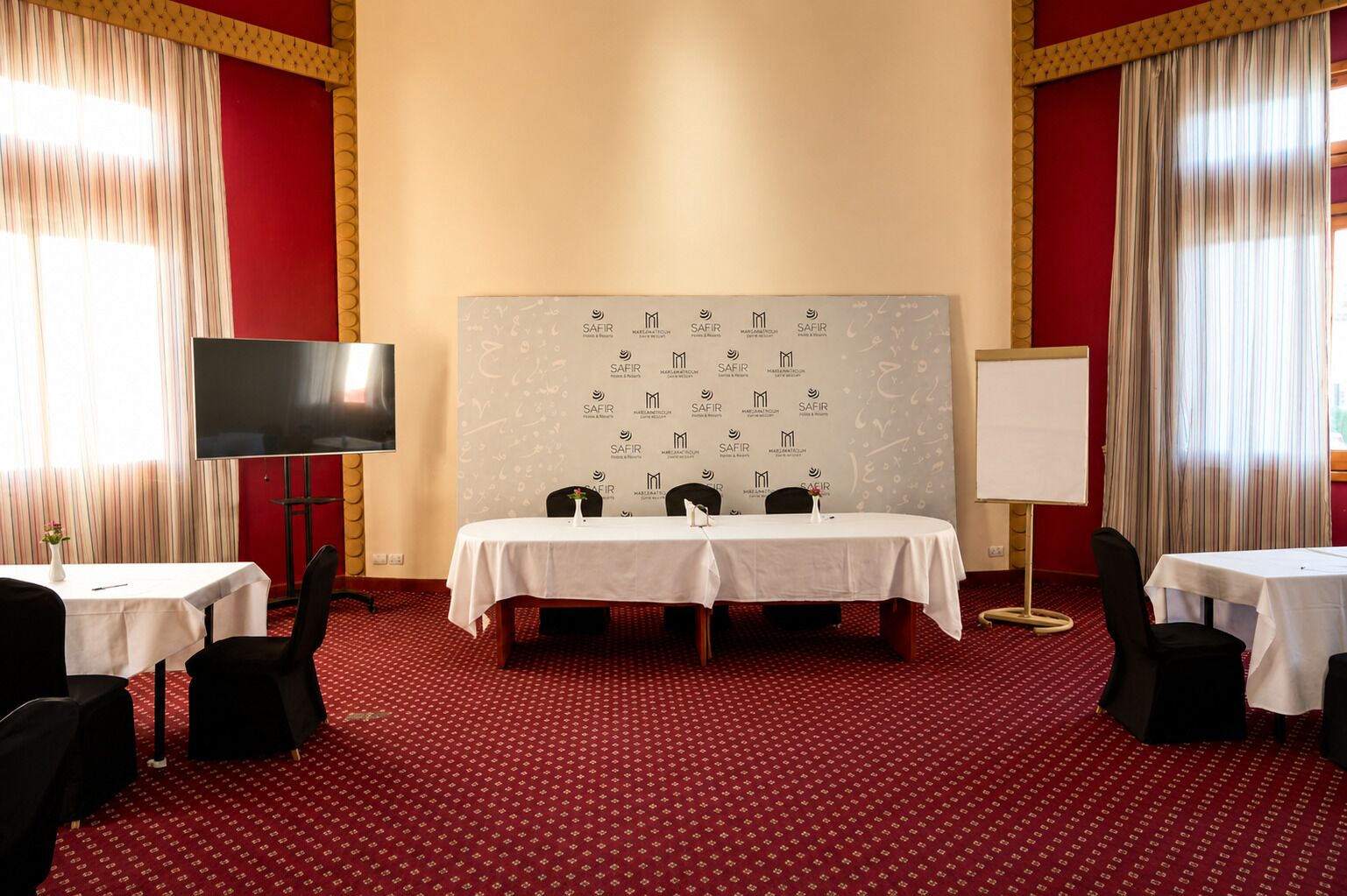 Une salle de conférence équipée d’un grand tableau blanc, d’un téléviseur et de deux tables avec des chaises.