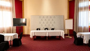 Une salle de conférence équipée d’un grand tableau blanc, d’un téléviseur et de deux tables avec des chaises.