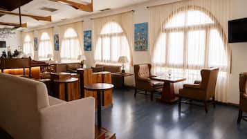 Un vaste espace de détente doté de nombreux sièges, notamment des canapés et des fauteuils, disposés autour d’une table centrale.