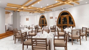 Comedor con vigas de madera, paredes de ladrillo blanco y mesas dispuestas para comer.