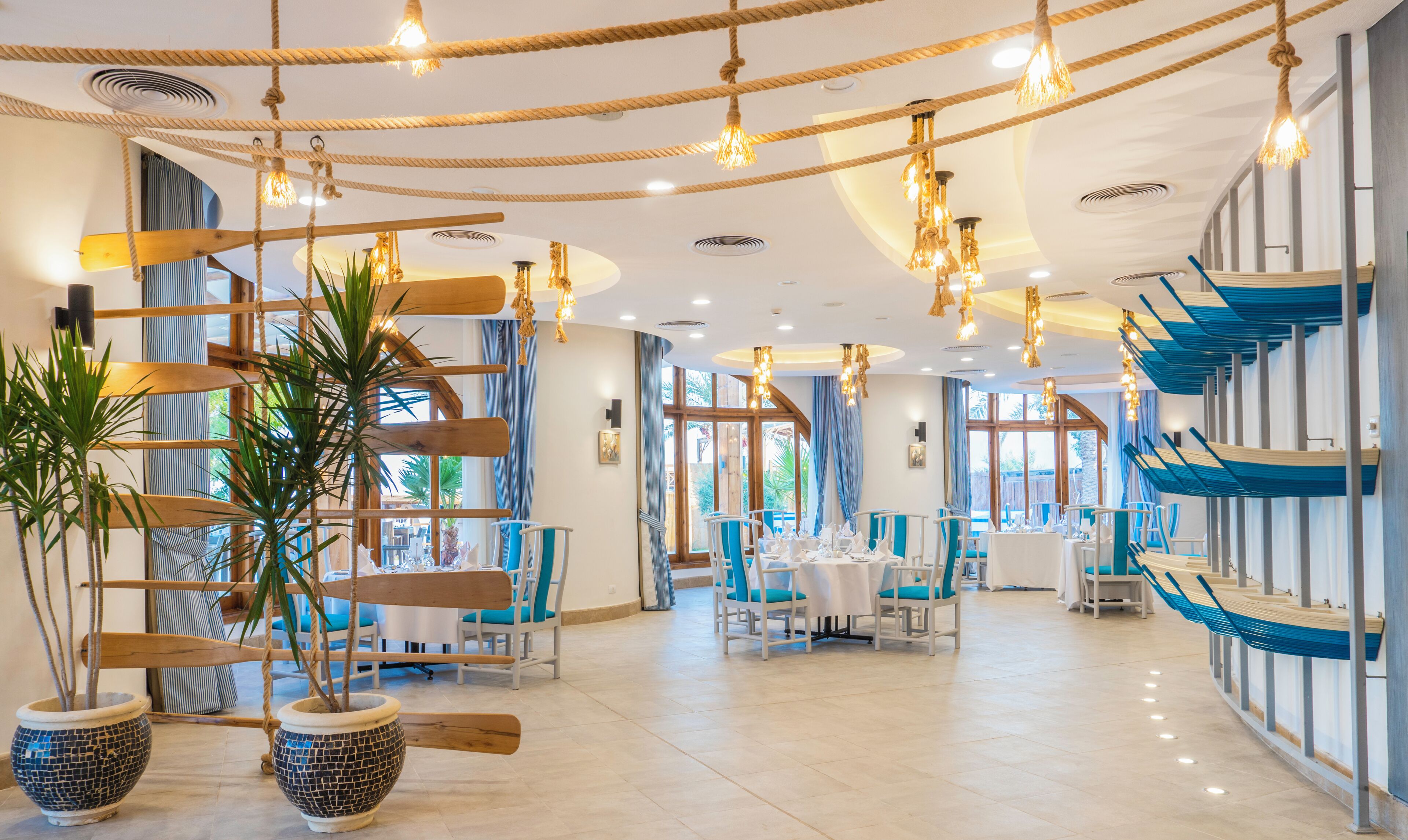A spacious dining area with high ceilings, hanging lights, and a view of the outdoors.