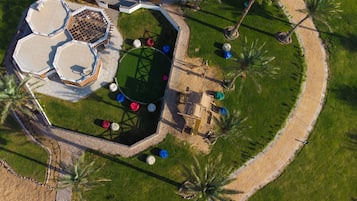 Eine Vogelperspektive eines Resorts mit einem sechseckigen Pool, Palmen und einem gepflasterten Weg.
