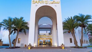 A modern building with a large arched entrance and palm trees in front. - Safir Dahab Resort (Dahab)