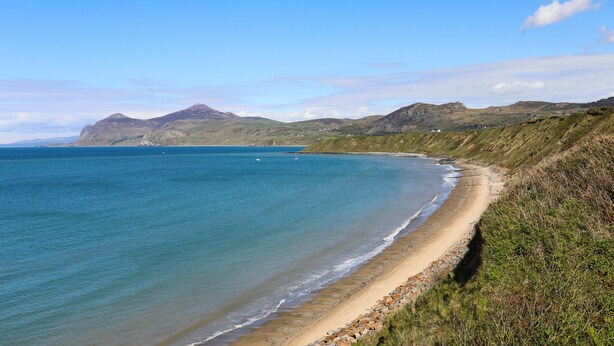 A coastal landscape with a sandy beach and rocky cliffs. - Ty Newydd Caravan (Pwllheli)