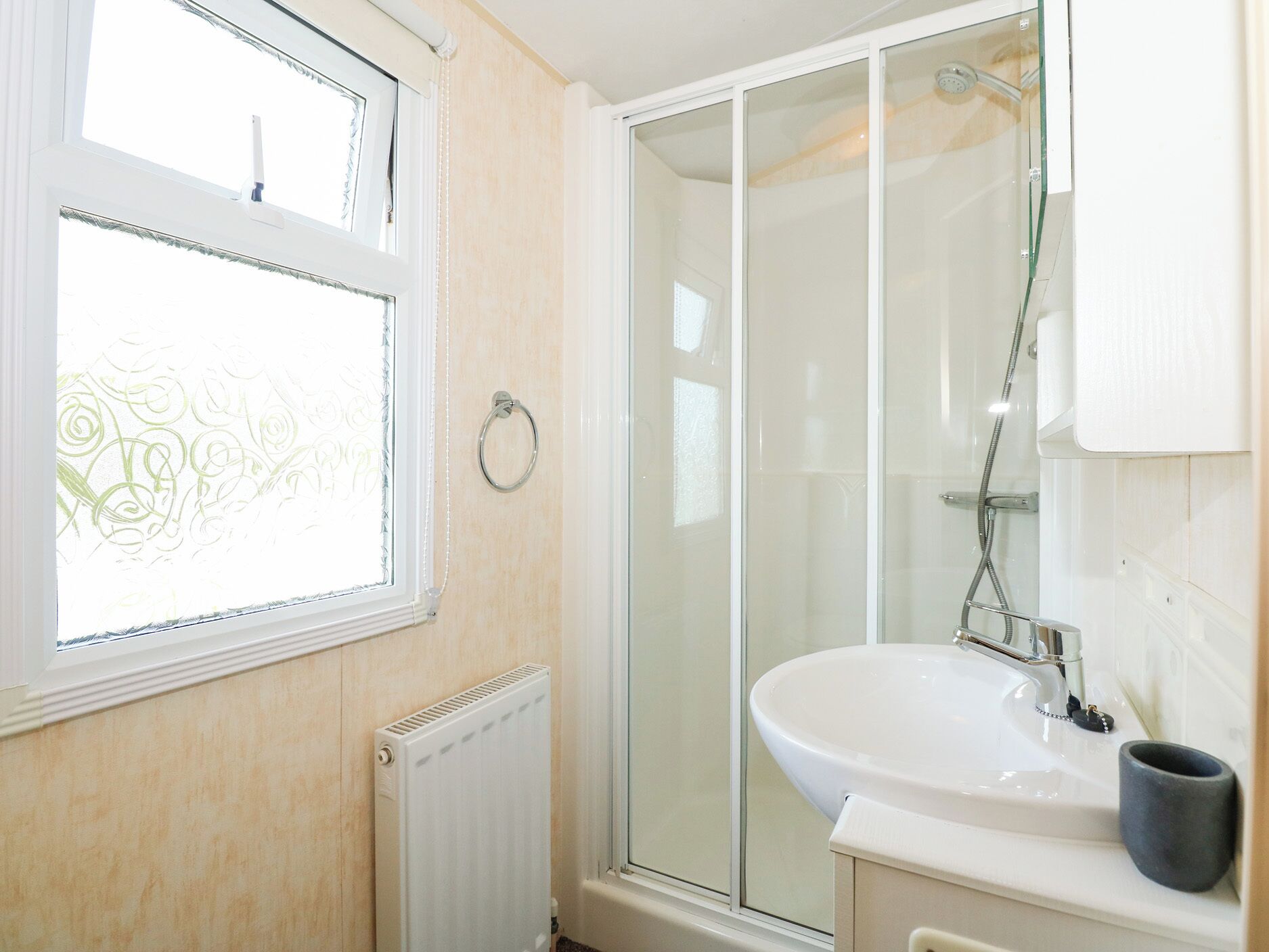 A bathroom with a window, a shower, and a sink.