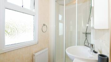 A bathroom with a window, a shower, and a sink.
