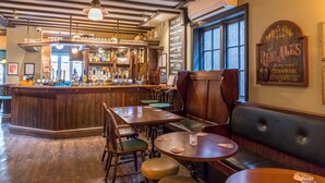 A cozy bar area with wooden furniture, a bar counter with various bottles, and a chalkboard menu. - Station Inn (Whitby)